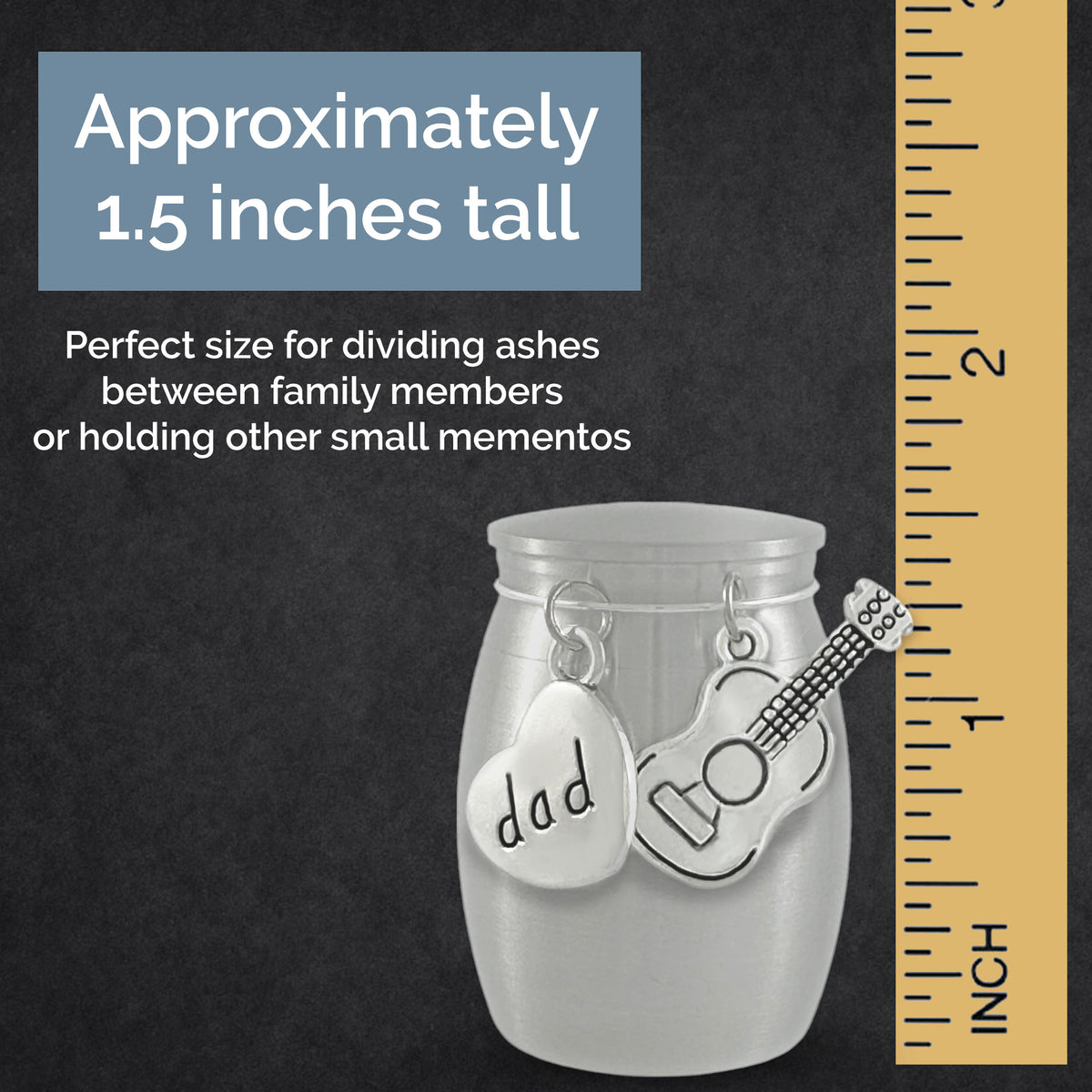 A small stainless steel urn with two silver charms, one heart-shaped and one guitar-shaped, displayed on a dark textured background with a wooden ruler on the right and text stating it is approximately 1.5 inches tall.