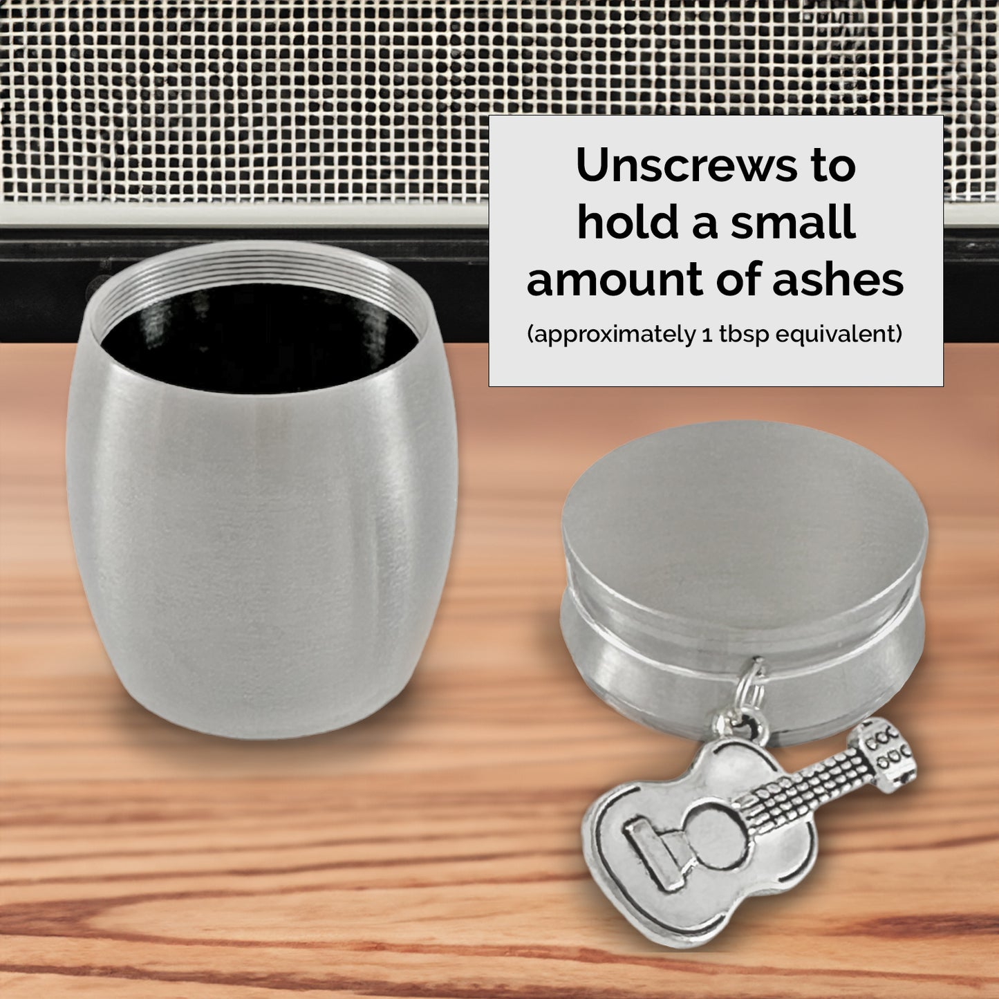 Tiny keepsake urn with guitar charm on the front. It is shown with the lid unscrewed. It holds a small amount of cremation ashes so you can give a small amount to each family member. The guitar charm is a memorial for someone who loved music or playing guitar.
