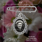 Silver-toned metal photo wedding pin with an oval photo frame and small wing charm, shown over a blurred floral background with measurement annotations indicating 2.5 inches wide by 2 inches long.