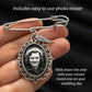 A silver-toned safety pin brooch wedding photo charm with an oval decorative frame holding a black-and-white portrait photo, shown resting on a person's fingers against a dark fabric background. Text overlays read 'Includes easy to use photo resizer' and 'Walk down the aisle with your missed loved one on your wedding day.