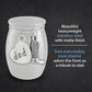 A silver-toned stainless steel keepsake jar with a matte finish, featuring a heart-shaped charm stamped with 'dad' and a cowboy boot charm, shown on a dark textured background with descriptive text.