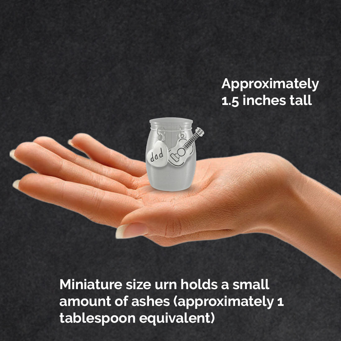 A hand holds a small brushed stainless steel urn ashes holder with a hanging heart charm stamped 'dad' and a guitar charm, against a dark background with text reading 'Miniature size urn holds a small amount of ashes (approximately 1 tablespoon equivalent).