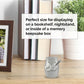 A small keepsake ashes holder urn with two silver charms, one shaped like a heart labeled 'dad' and the other shaped like a guitar, displayed on a wooden tabletop in a home setting. A text overlay explains the mini urns use for bookshelves, nightstands, or memory keepsake boxes.
