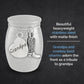 A silver small memorial urn jar with a matte finish, featuring engraved and shaped charms on the front: a heart charm reading 'Grandpa' and a cowboy boot charm. Text on a dark background describes the product as a stainless steel tribute jar with these charms.