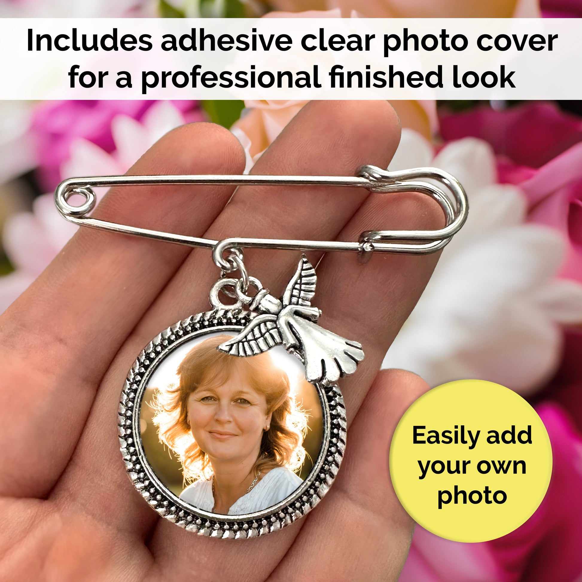 Memorial photo charm pin with angel charm shown in the palm of a hand for size reference. There are flowers in the background. Text banner reads "Includes adhesive clear photo cover for a professional finished look". Yellow circle call out reads "Easily add your own photo"