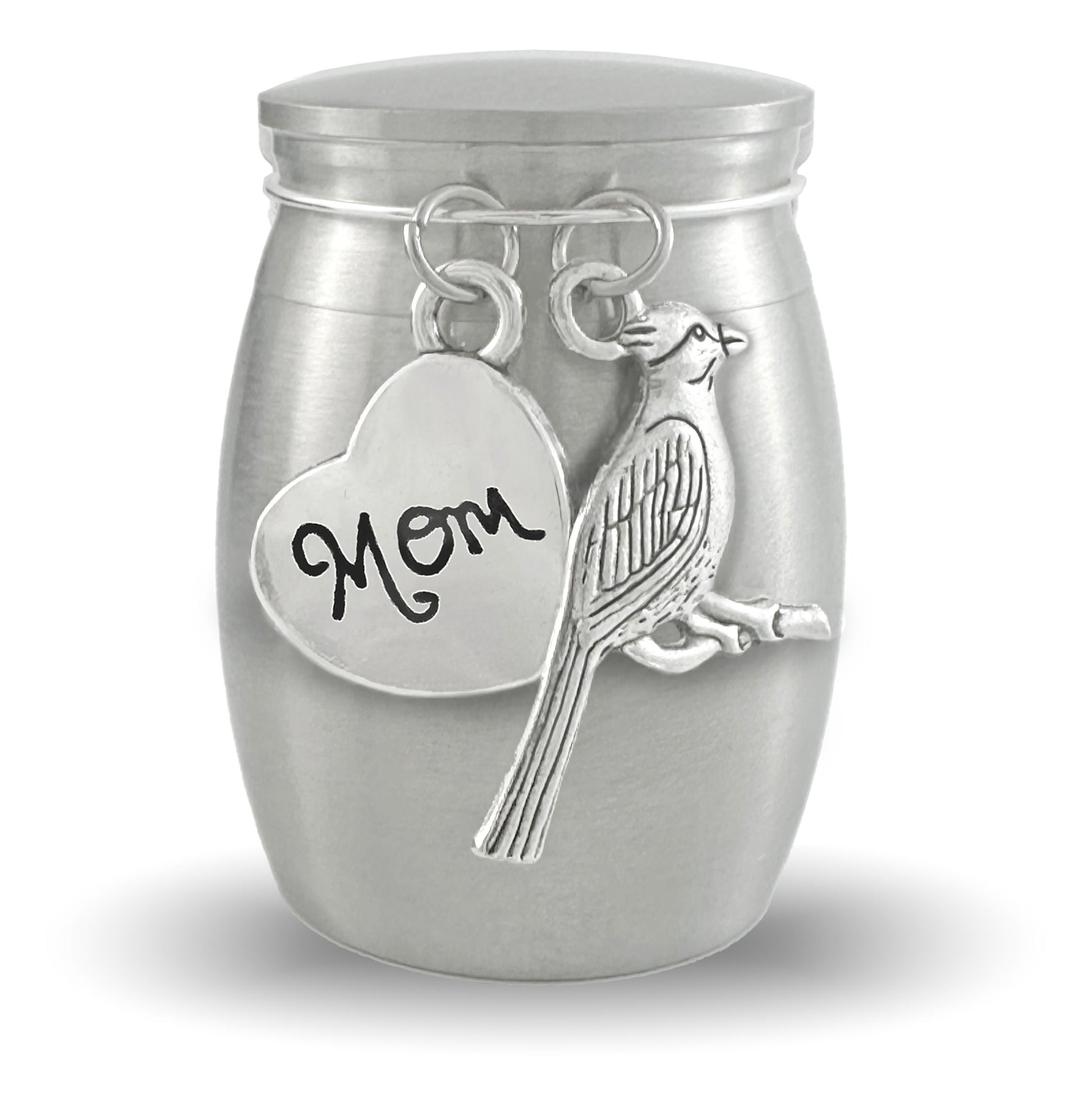 A silver cremation urn shaped like a small jar, featuring a heart-shaped charm engraved with 'Mom' and a cardinal charm, shown on a white background.