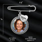 Silver photo frame safety pin brooch with a heart charm engraved 'Mom' and a circular photo insert, shown with measurement labels on a black satin background.