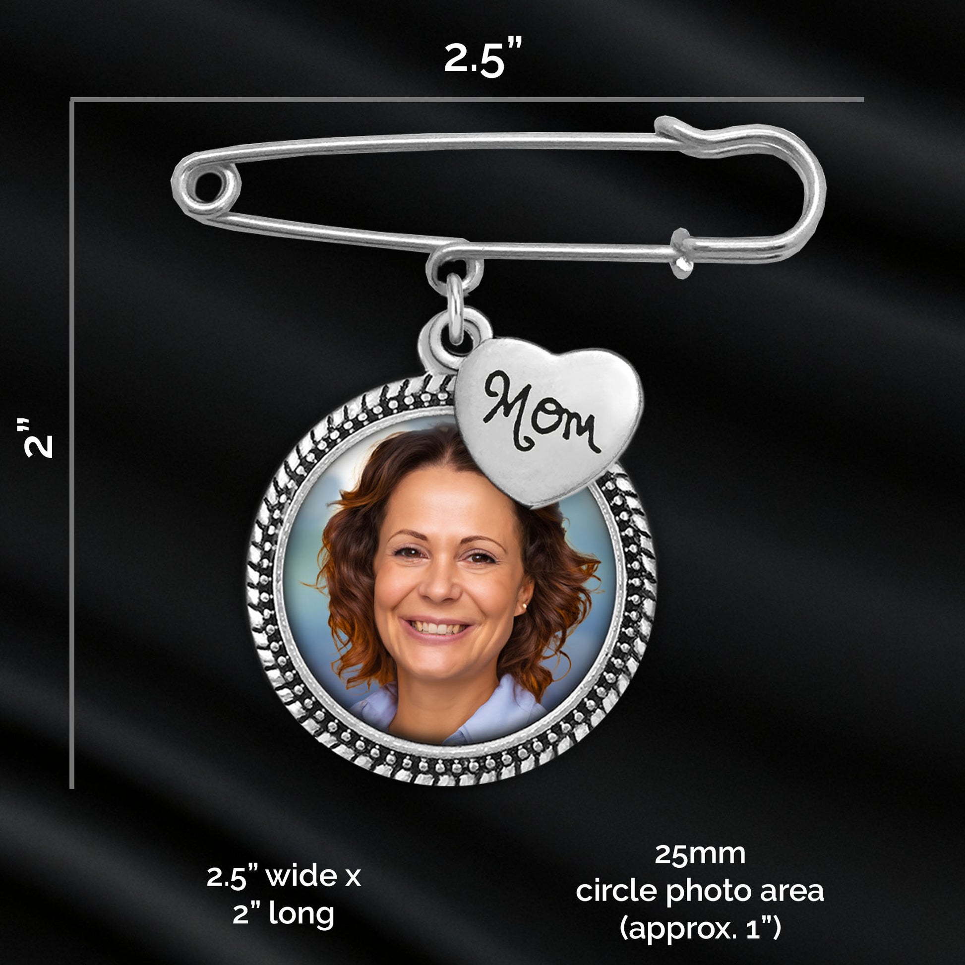 Silver photo frame safety pin brooch with a heart charm engraved 'Mom' and a circular photo insert, shown with measurement labels on a black satin background.