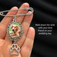 Silver brooch with a photo of a dog and a paw print charm, held in a hand against a black background.