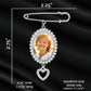 Silver oval photo pendant memorial pin with a heart-shaped dangling charm, shown on a black satin background with printed dimensions and text indicating photo size measurements.