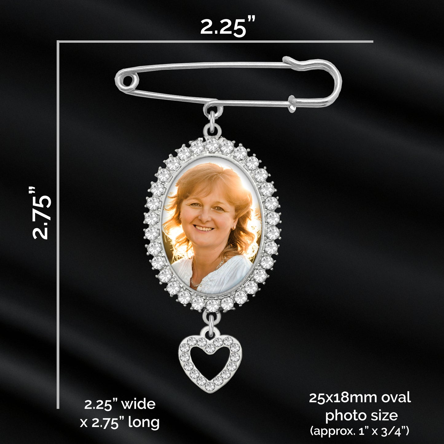 Silver oval photo pendant memorial pin with a heart-shaped dangling charm, shown on a black satin background with printed dimensions and text indicating photo size measurements.