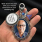 A hand holding a silver-toned keepsake pendant with an oval photo frame, a round photo charm, a something blue angel charm. White text in the upper left reads, 'Walk down the aisle with your missed loved one on your wedding day.