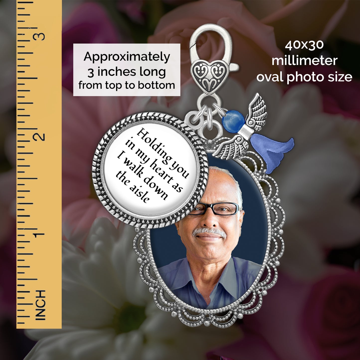 Silver memorial pendant charm with an oval photo frame holding a portrait of an older man, a round charm reading 'holding you in my heart as I walk down the aisle,' a small blue angel charm, shown with a ruler scale and text noting 40x30 millimeter oval photo size and approximately 3 inches long.