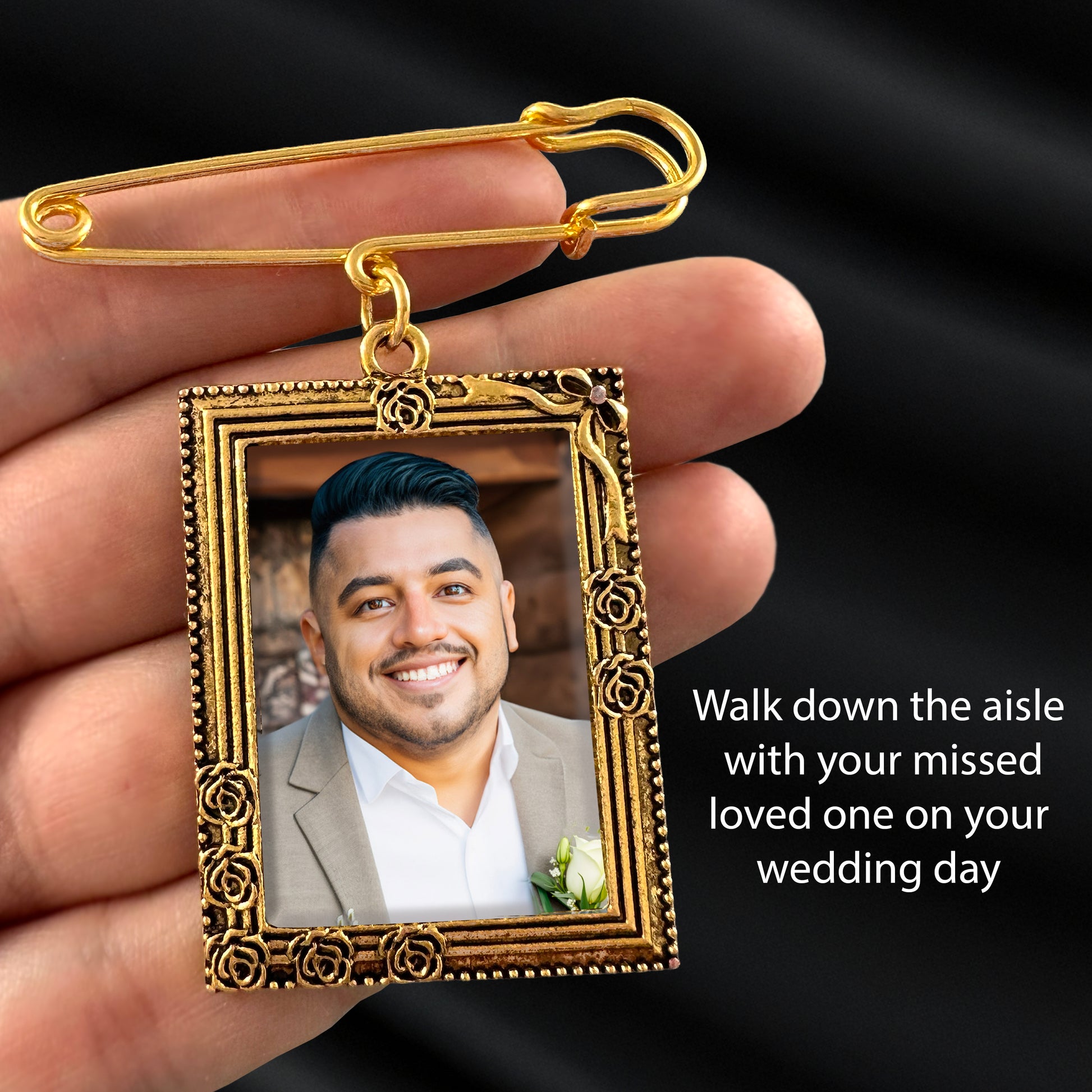 Gold-framed pendant with a photo of a man, held by a hand against a black background.